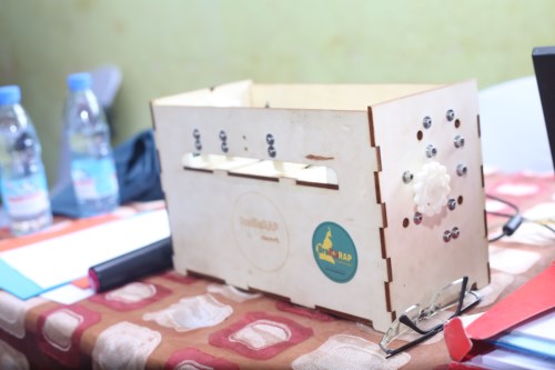 A plywood BrailleRAP placed on a table, the top hatch is open.