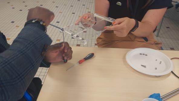 Two people assemble the paper tray of a BrailleRAP.