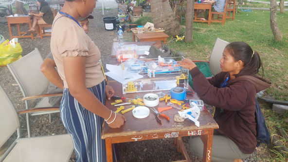 A BrailleRAP assembly workshop, 2 people use tools and spare parts to assemble a BrailleRAP.