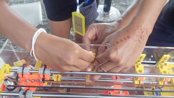 A person finishes assembling the top carriage of a BraileRAP during workshops.