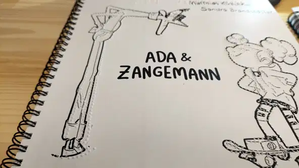 La couverture du livre. Ada à droite fait face à Zangemann à gauche. Le titre et quelques informations sont embossés en Braille, les dessins d'Ada et Zangemann sont imprimé en noir et embossé.